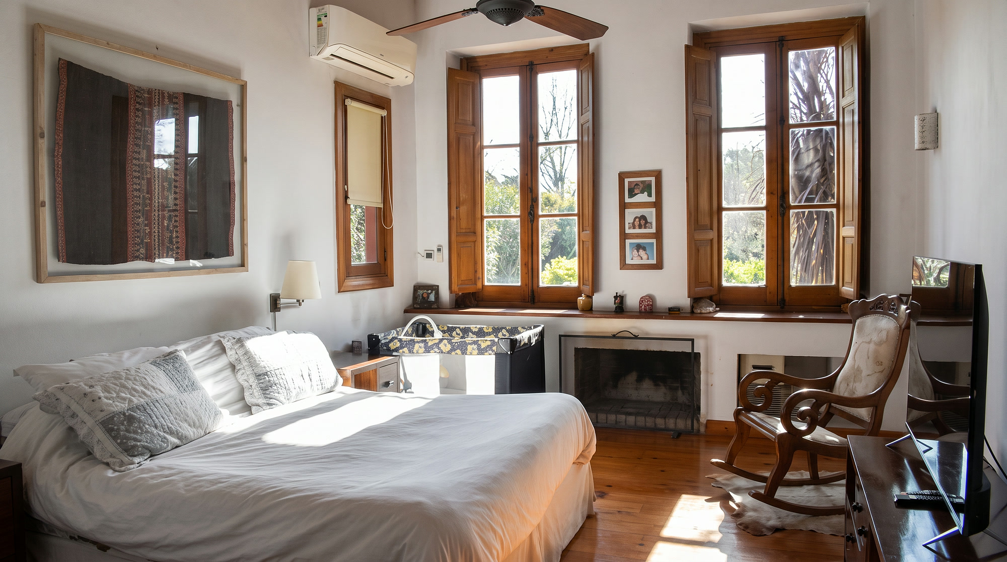 Dormitorio con cama doble, hogar y mecedora junto a los ventanales
